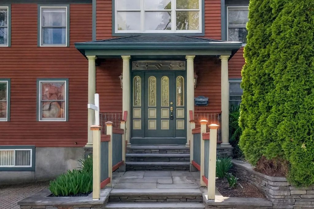 The covered front porch of 8 Hawthorne St, with original columns and a glass-paneled front door