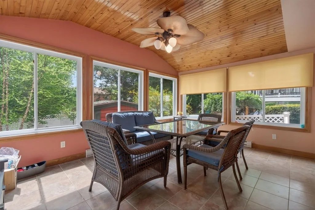 The heated sunroom at 8 Hawthorne St under a vaulted wood ceiling with a ceiling fan, opening to the rear deck