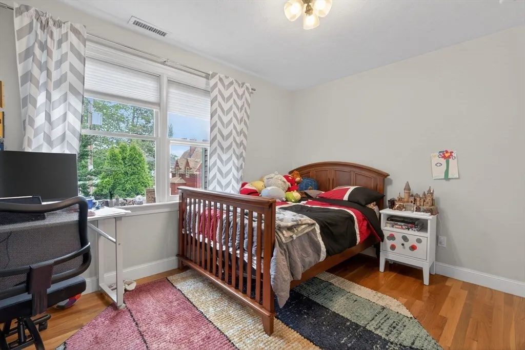 A second-floor bedroom at 8 Hawthorne St in soft white with warm oak floors and bright windows