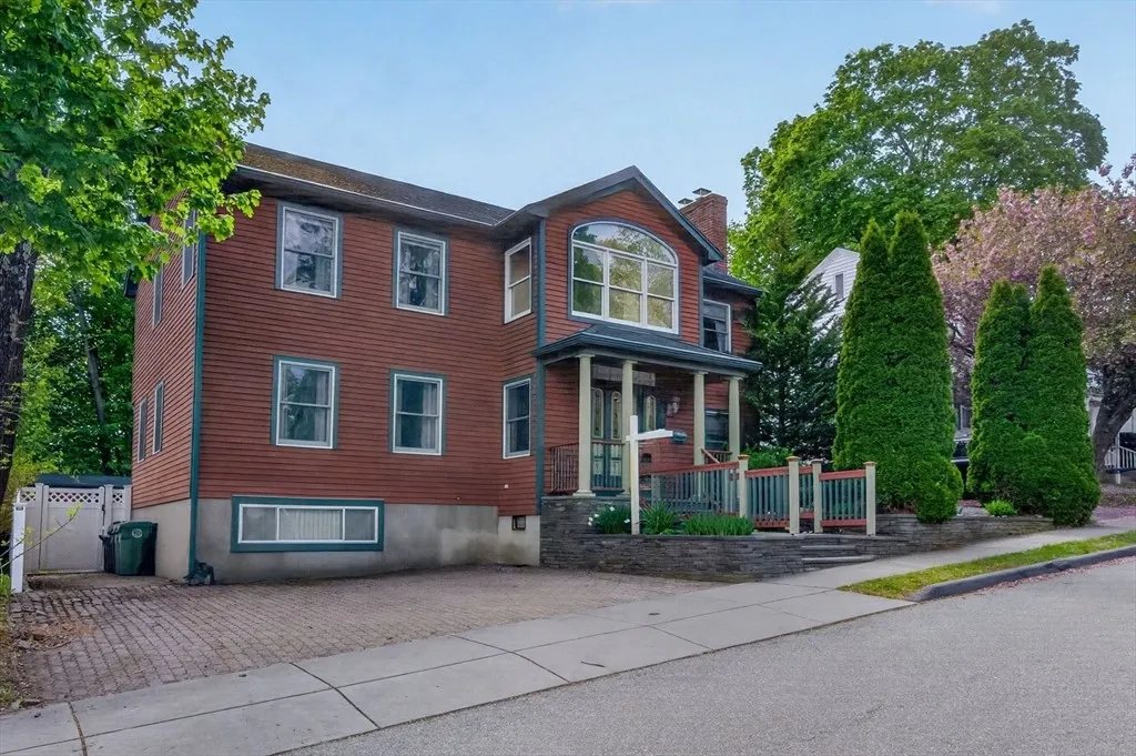 Front three-quarter elevation of 8 Hawthorne St, a brick-red three-story Colonial with white trim and a covered front porch on a tree-lined street in Watertown, Massachusetts